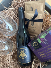 Load image into Gallery viewer, A curated gift basket or box containing a bottle of Grape Society wine, a purple box of Butterfields Selects fruit pastries, kraft paper bags from Wild Barrel Co., and two clear stemmed glasses arranged in shredded straw filler.