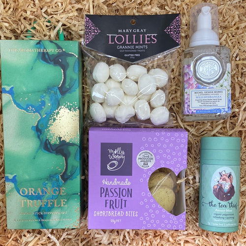 gift box of cookies, room diffuser soap tea and lollies in purple and green colours